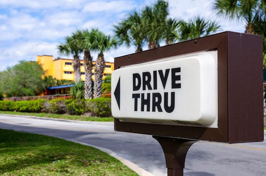 drive thru sign with brown border and palm trees in background
