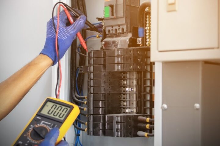 yellow electrical meter held by a hand with a blue glove testing an open circuit for an electrical inspection
