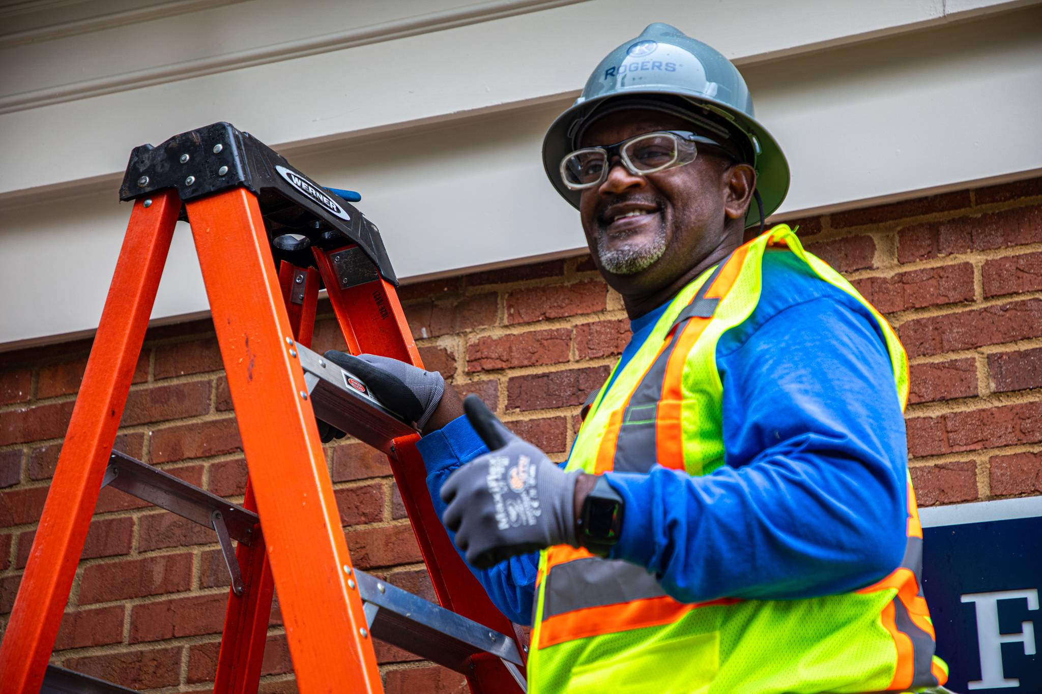 Roger's technician giving thumbs up on ladder.