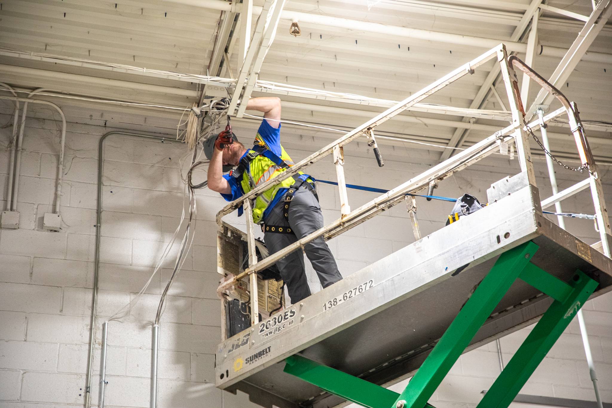 NHI - 3 Technician on lift installing power box.