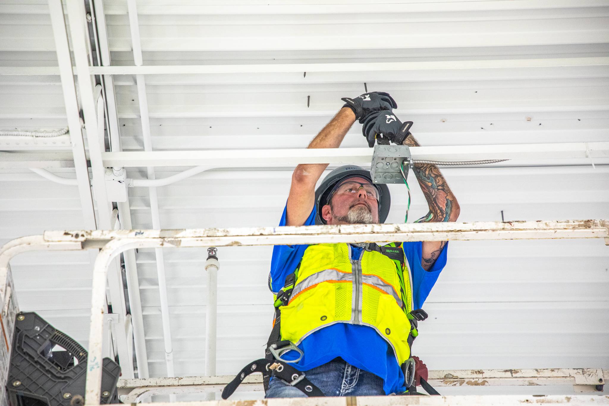 Technician screwing power box to ceiling.