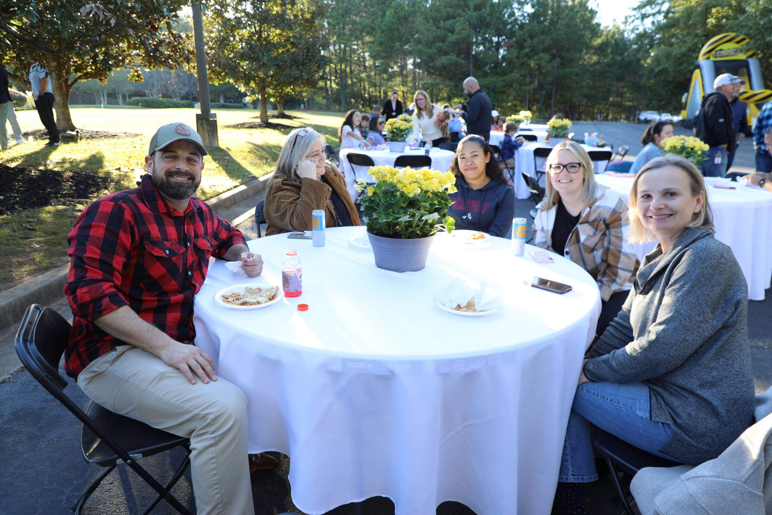 Rogers Electric employees sitting at white table smiling while at Fall Festival