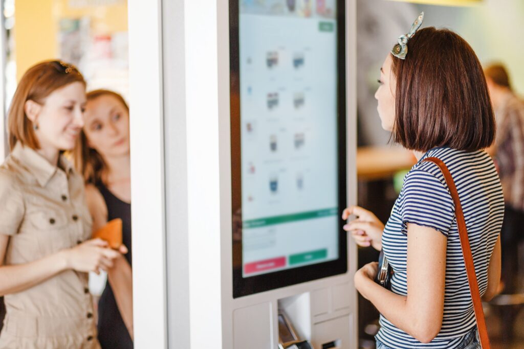 girl ordering off of a digital menu board in a restaurant