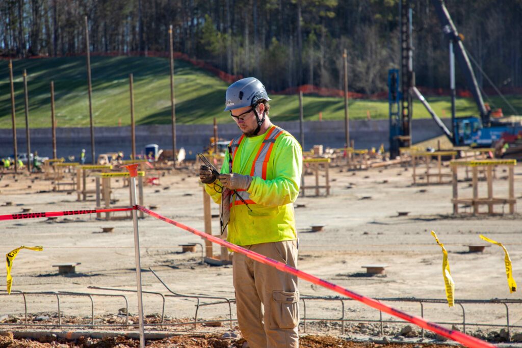electrician on the scene of a construction site putting up danger tape wearing all PPE gear