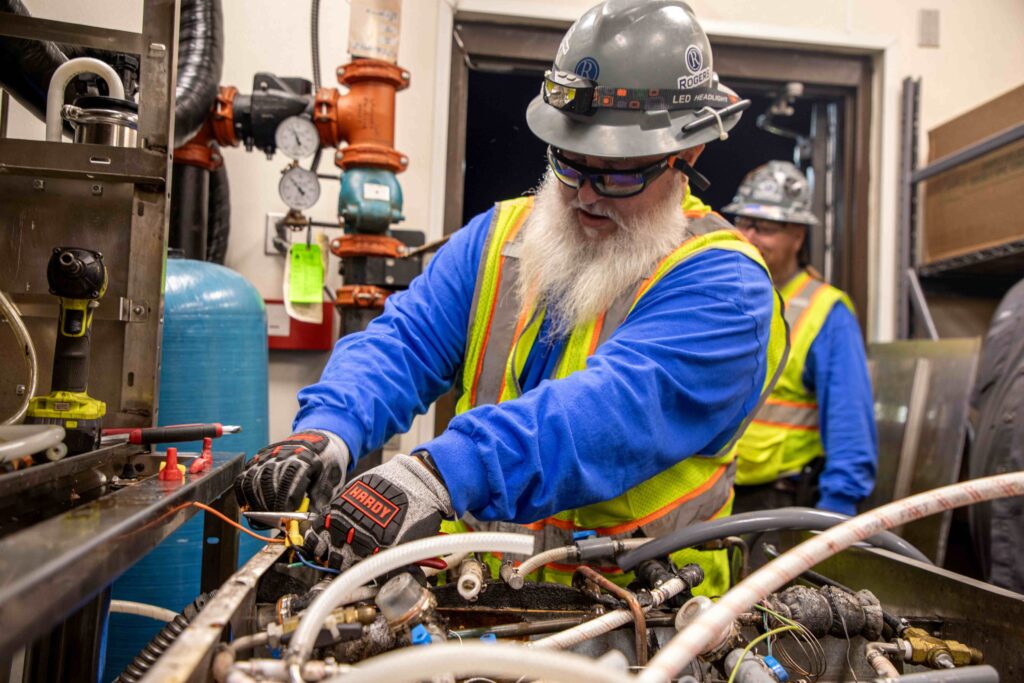 Rogers electrician disconnecting machine with wires in all of his PPE gear