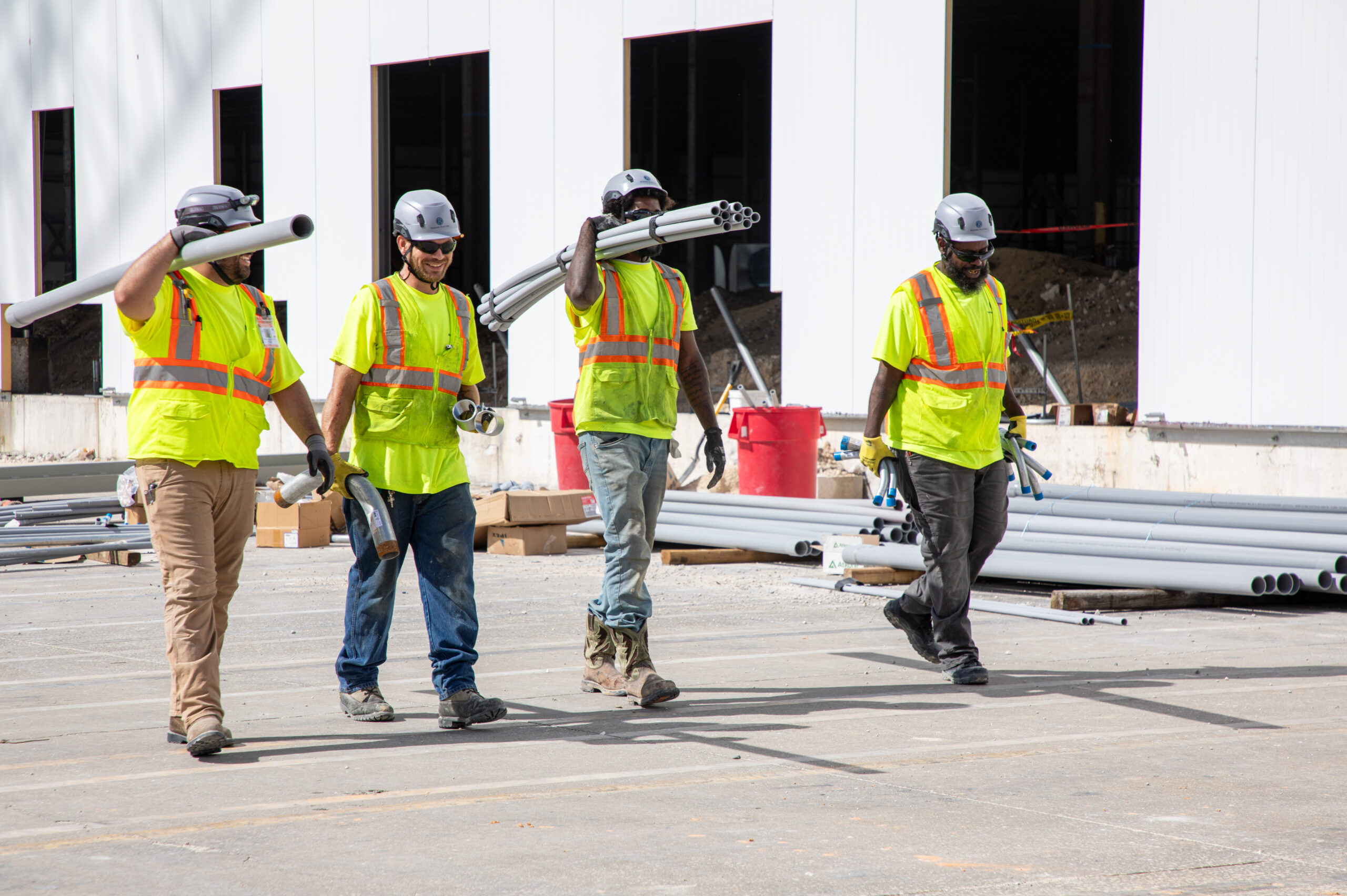 electricians walking carrying equipment outside near job site