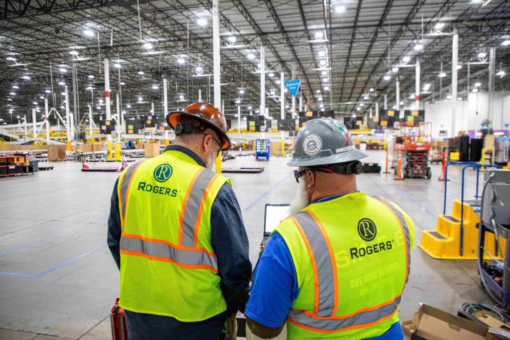 Two electricians collaborating in a warehouse.