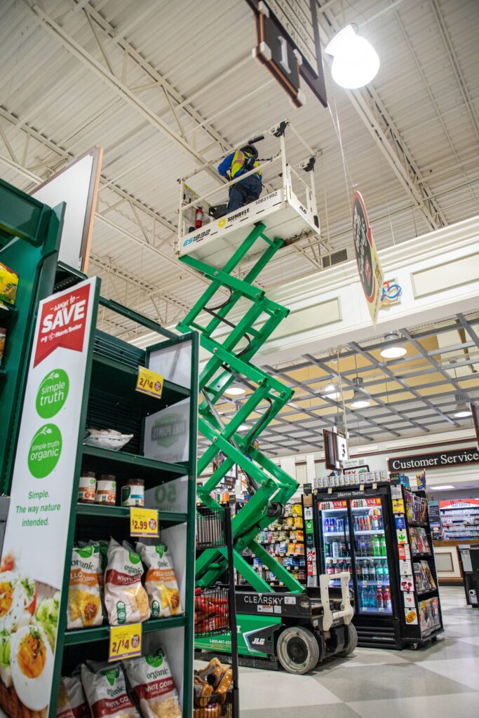 Electrician operating scissor lift in supermarket.