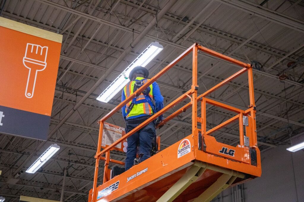 Commercial electrician installing lights in a home improvement store.