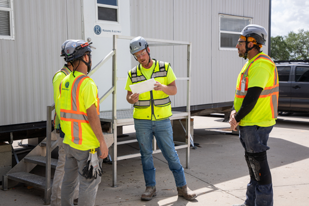 Three electricians reviewing plans on a jobsite.