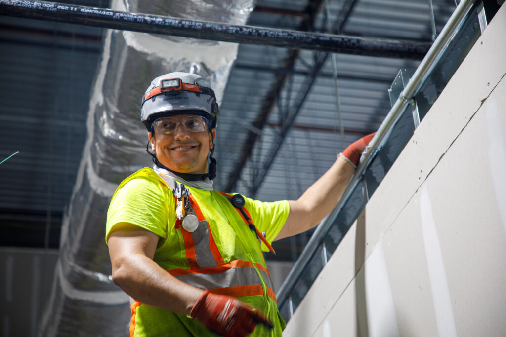 Electrician in safety gear installing conduit in a commercial building, capturing the hands-on work behind modern power upgrades.