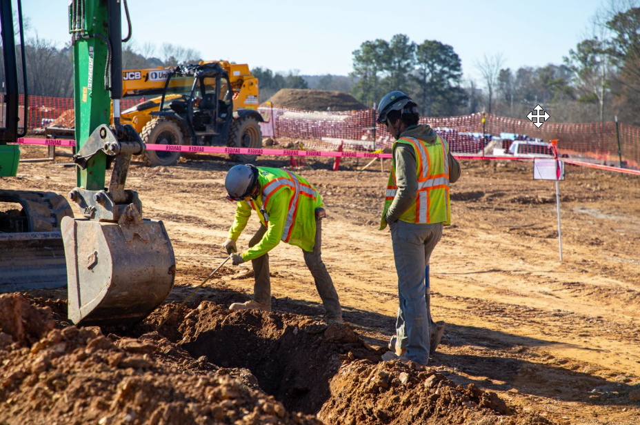 Electricians preparing underground conduit at a commercial jobsite, supporting new power systems for expanding facilities.