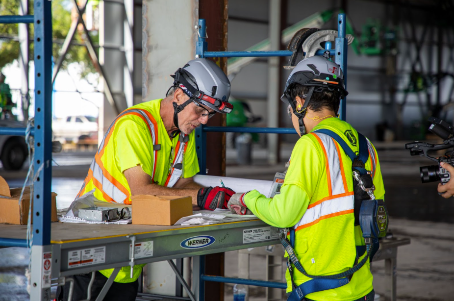 Rogers Electric technicians reviewing electrical plans at a commercial construction site, coordinating work for modern building infrastructure.
