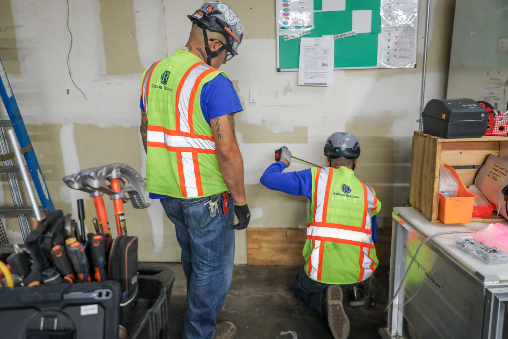 Rogers Electric team measuring and marking wall locations during a commercial electrical remodel.