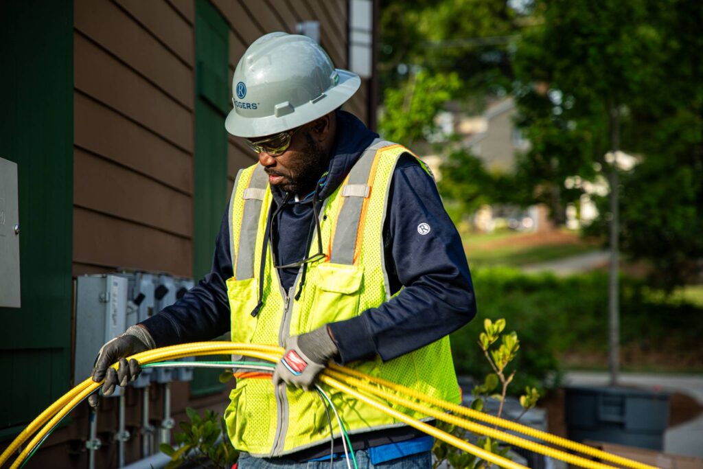 Rogers Electric electrician installing conduit and electrical cabling for modern sports facility technology.