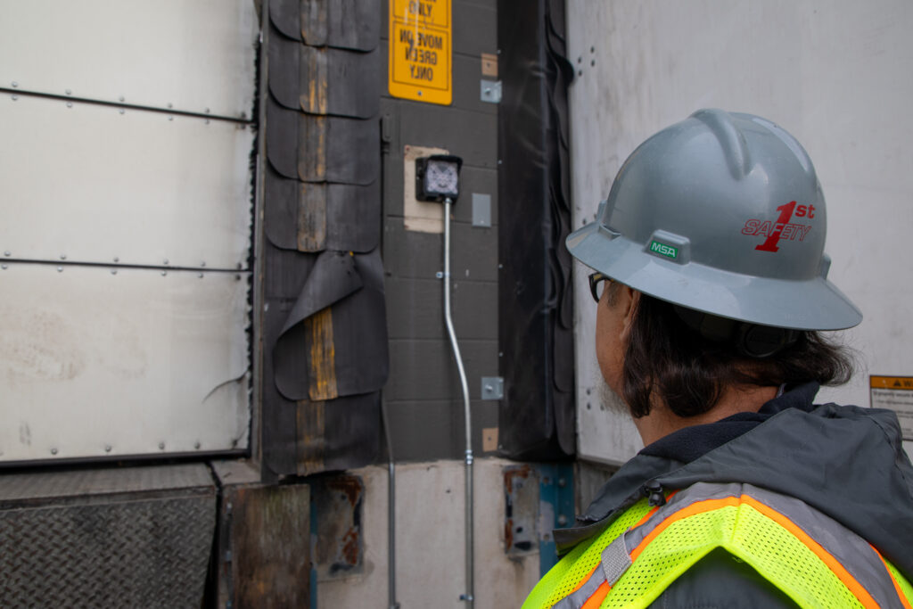 Electrical technician inspecting power connection at commercial loading dock.