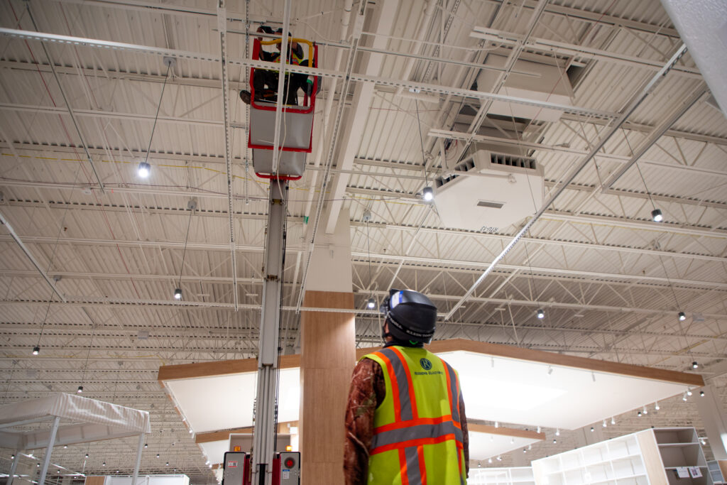 Electricians installing overhead electrical systems during retail store rollout renovation.