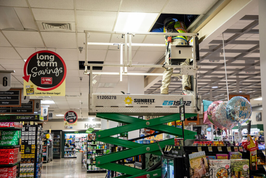 Technician installing vertical LED fixtures as part of a commercial lighting upgrade to improve lighting system performance and efficiency