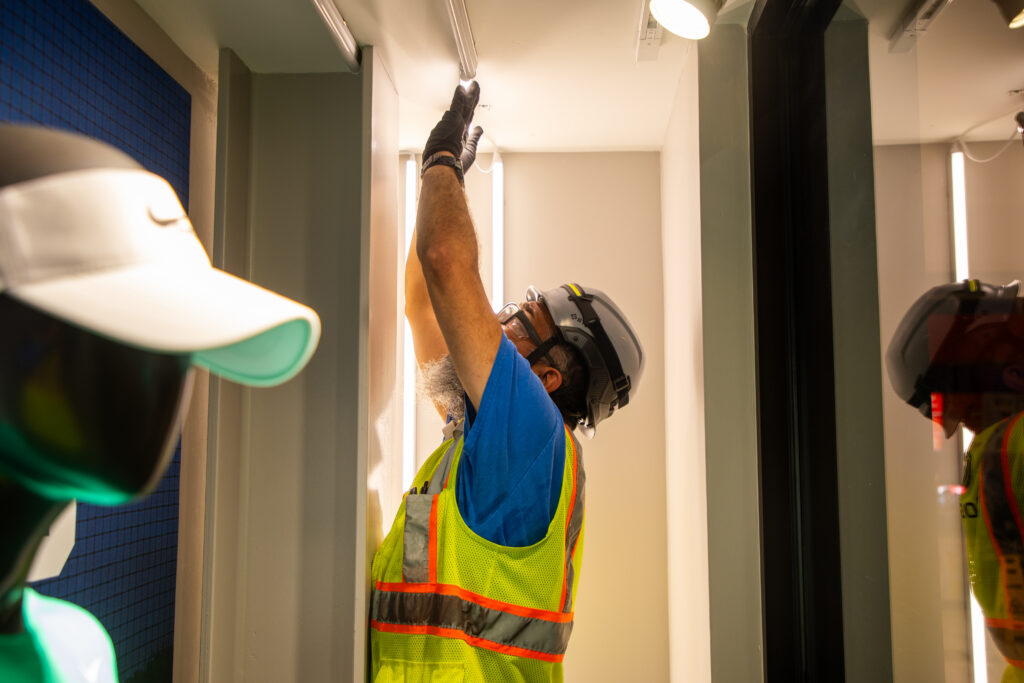 Technician installing vertical LED fixtures as part of a commercial lighting upgrade to improve lighting system performance and efficiency