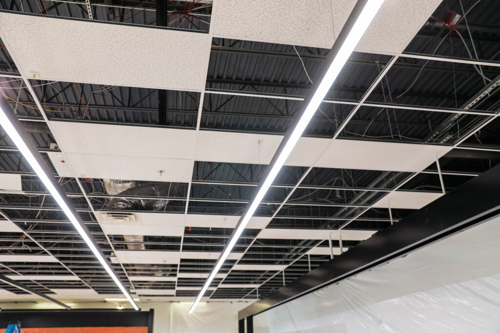 Commercial lighting retrofit with linear LED fixtures and open ceiling infrastructure designed for energy savings and lighting rebate programs.